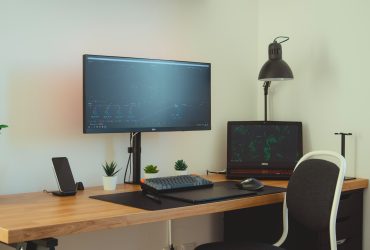 black flat screen computer monitor with single monitor arm on brown wooden desk